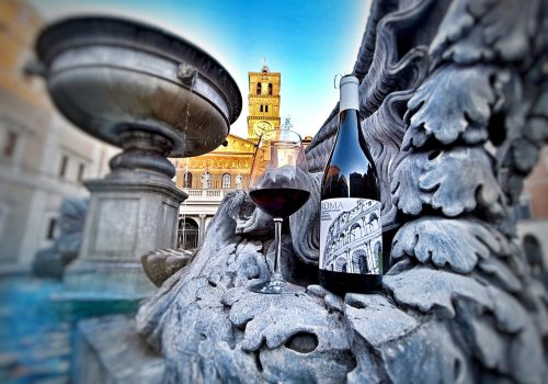 botella de vino y una copa de vino tinto colocadas sobre una estructura de piedra