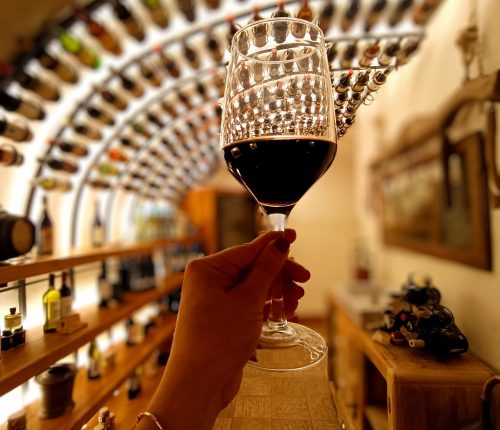Mano que sostiene un vaso lleno de vino tinto